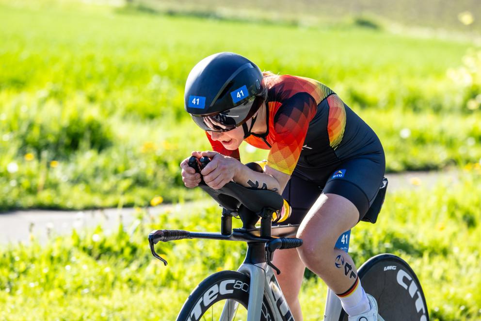 Eine Sportlerin fährt in geduckter Haltung Rennrad