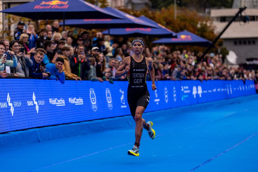 Eine Triathletin läuft auf dem blauen Teppich den Zielkorridor eines Triathlons dem Ziel entgegen