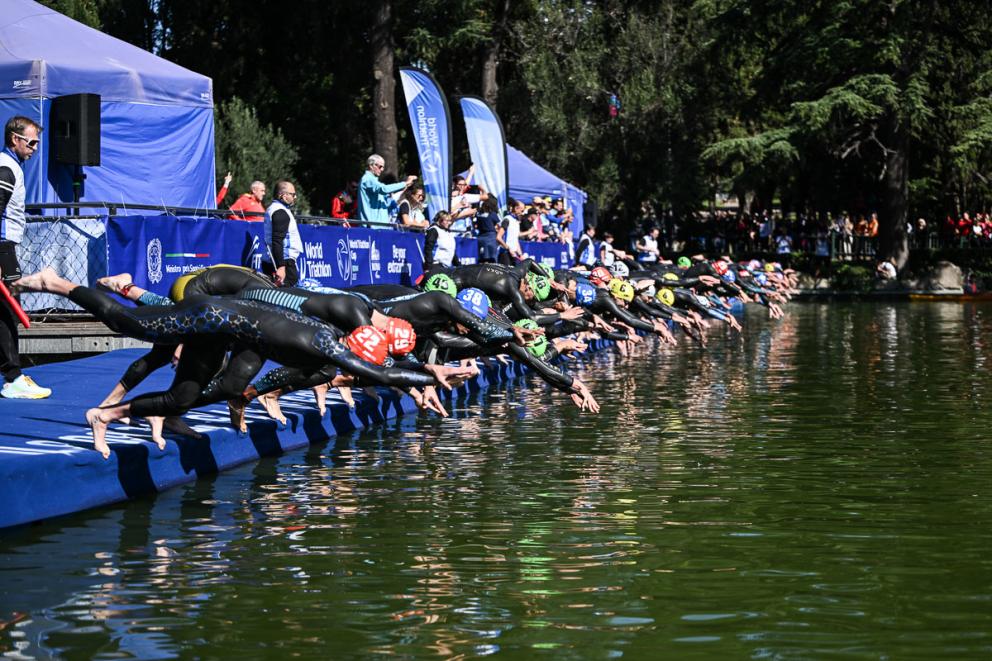 Mehrere Triathleten springen beim Start eines Startes nebeneinander mit einem Kopfsprun ins Wasser
