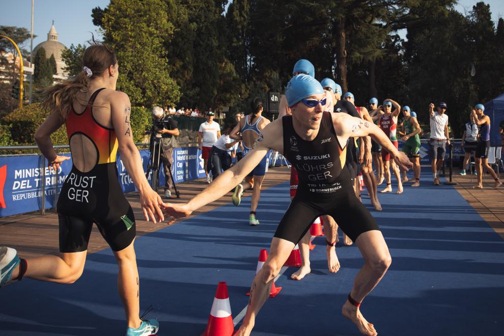 Eine Triathletin schlägt in einem Mixed-Staffel-Rennen mit dem nachfolgenden Triathleten ab