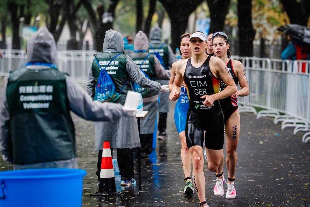 Mehrere Triathletinnen laufen an einer Wasser-Verpflegungsstelle vorbei