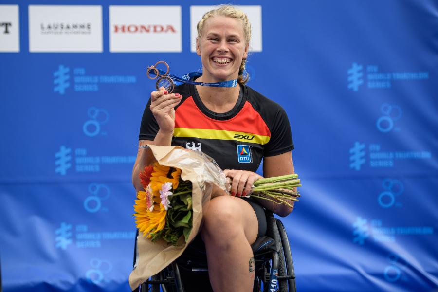 Athletin im Rollstuhl zeigt stolz ihre Medaille.