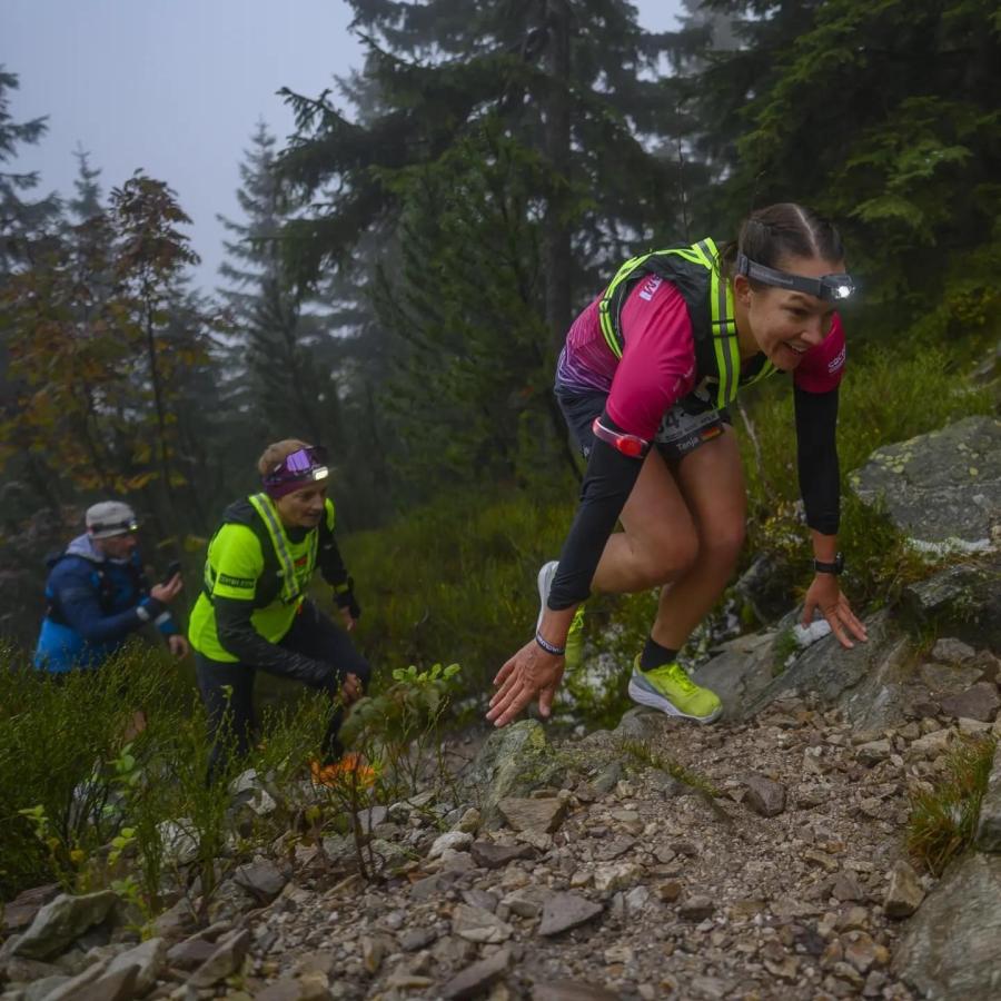 Frau klettert einen Berg hoch, hinter ihr folgen zwei weitere