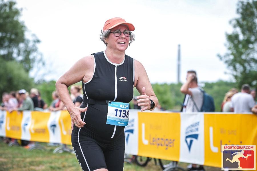 Marlies Becker läuft an gelben Banner vorbai, dahinter Zuschauer, die anfeuern