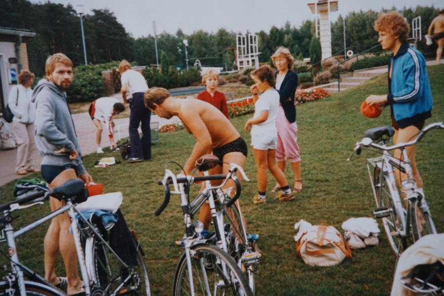 Menschen auf einer Wiese im Freibad mit Rennrad und in Badekleidung