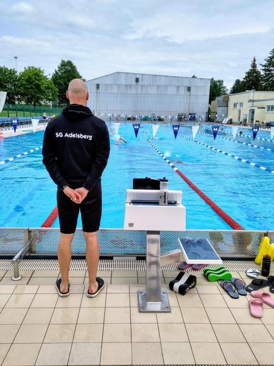 Trainer steht am Beckenrand