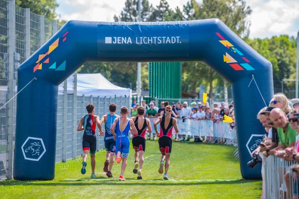 Jugendliche laufen durch Werbebogen