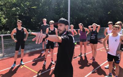 Ein Trainer zeigt eine Gruppe von Athlet*innen den Weg