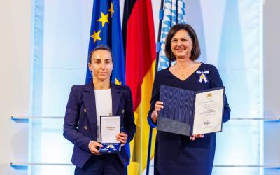 Eine geehrte Preisträgerin präsentiert gemeinsam mit ihrer Laudatorin eine Urkunde und eine Medaille
