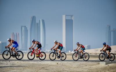 Elite-Triathleten auf Radstrecke vor Abu Dhabi Skyline