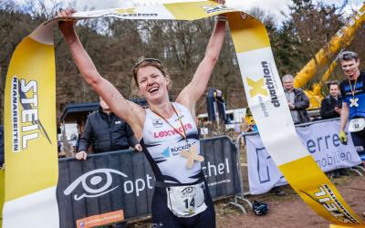 Eine Duathletin jubelt im Ziel mit dem Zielband in der Hand über ihren Sieg