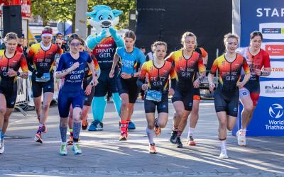 Athletinnen der Duathlon WM in Alsdorf laufen an der Startlinie los, im Hintergrund Maskottchen Trinity