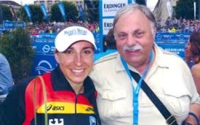 Hein Rüger hält legt den Arm um Athletin und beide lächeln in die Kamera