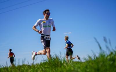 Para Triathlet beim Laufen mit grüner Wiese und blauem Himmel