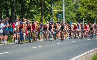 Junge Athleten auf dem Fahrrad im Windschatten, an der Strecke stehen viele Zuschauer