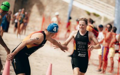 Eine Triathletin klatscht mit einem Triathleten ab und schickt ihn im Rahmen einer Staffel auf die Reise