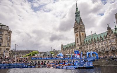 Rund 15 Triathleten springen bei einem Start von einem künstlichen Steg aus ins Wasser