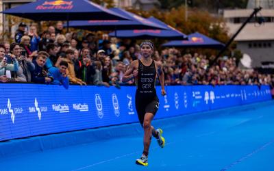 Eine Triathletin läuft auf dem blauen Teppich den Zielkorridor eines Triathlons dem Ziel entgegen