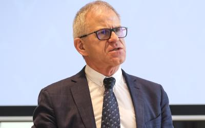 Ein Portrait eines älteren Mannes in Anzug, der eine Brille trägt
